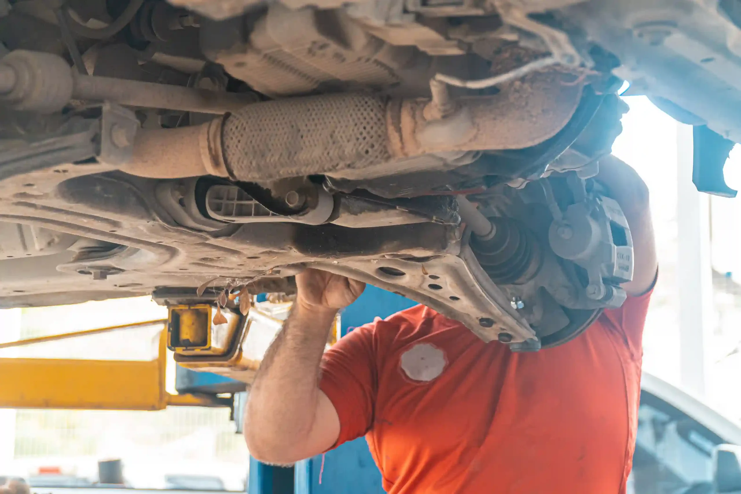 Mechanic inspecting car suspension for warning signs