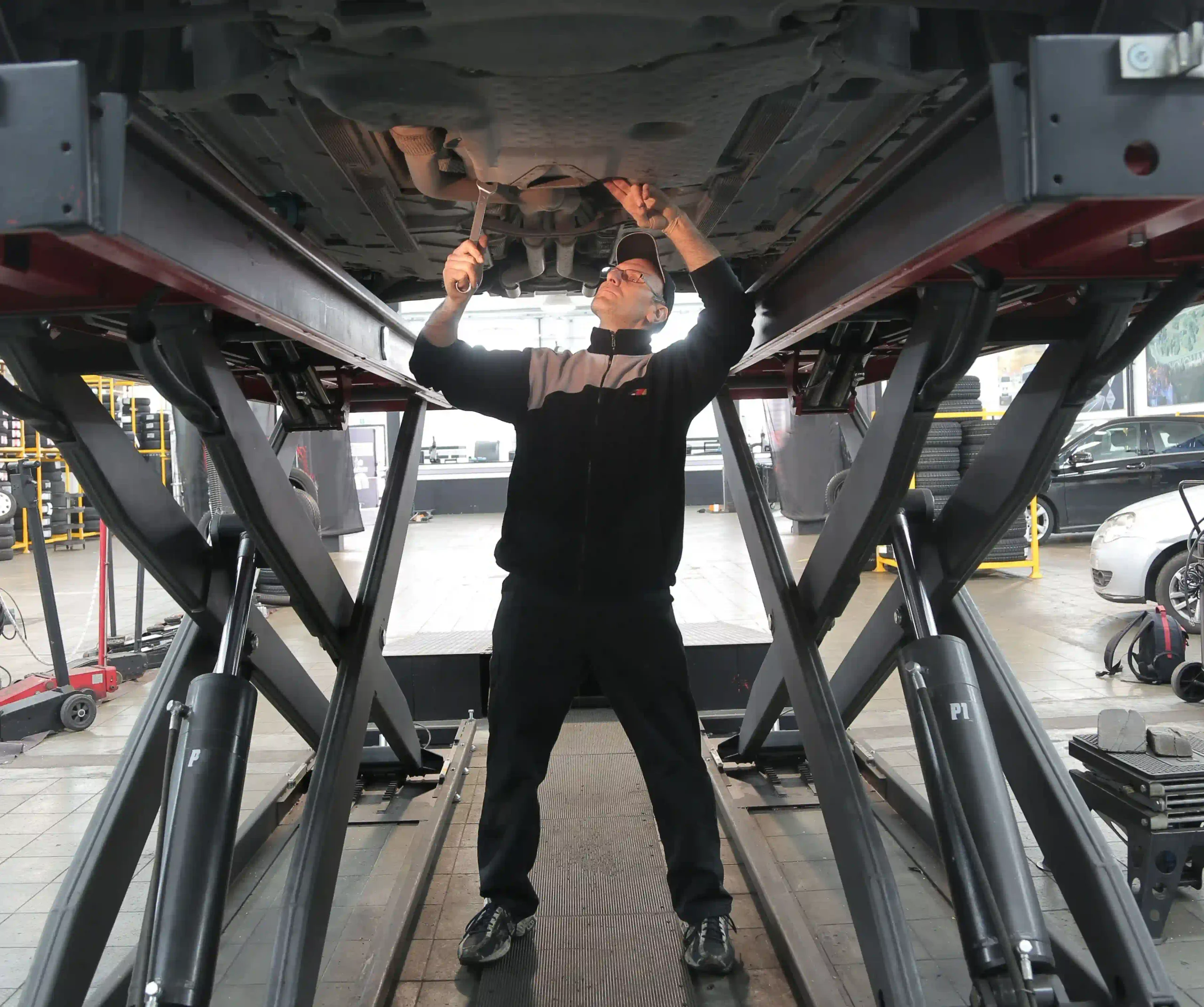 Mechanic checking the underside and suspension of a European car during inspection