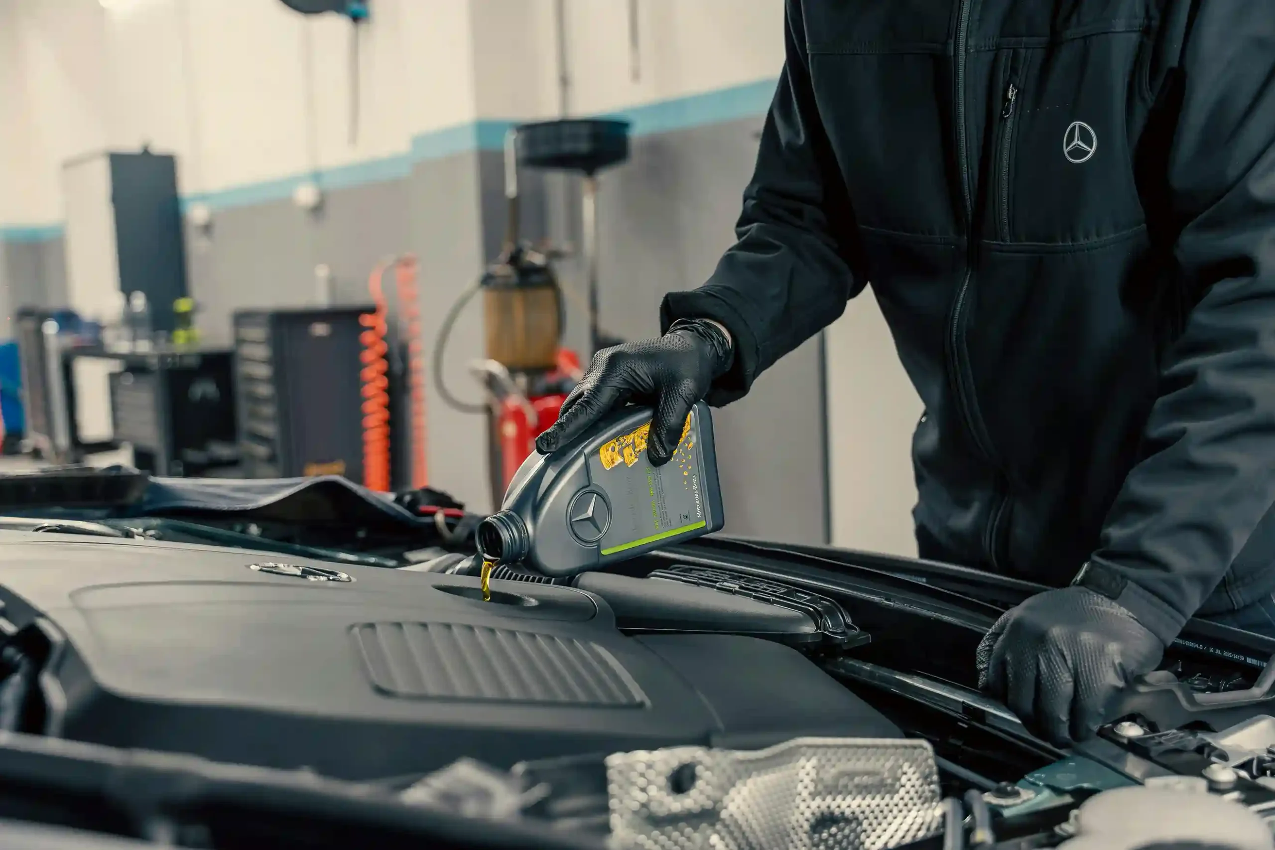 Mechanic pouring oil into a car engine during an oil change